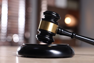 Photo of Judge's gavel and sound block on wooden table against blurred background, closeup