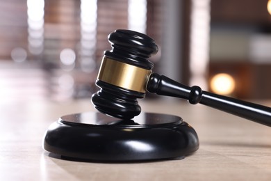 Photo of Judge's gavel and sound block on wooden table against blurred background, closeup