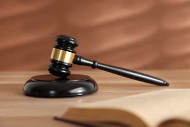 Photo of Judge's gavel, sound block and book on wooden table against coral background, selective focus