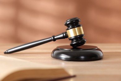 Photo of Judge's gavel, sound block and book on wooden table against coral background, selective focus
