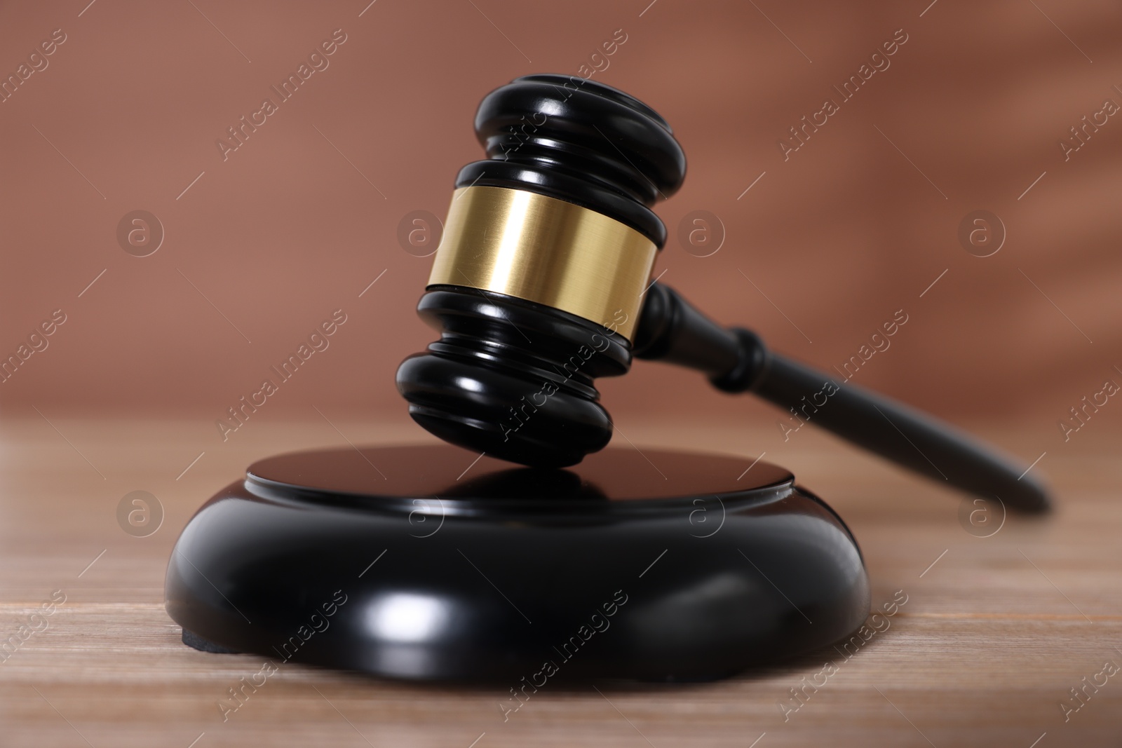 Judge's gavel and sound block on wooden table against brown background, closeup Photo of Judge's gavel and sound block on wooden table against brown background, closeup