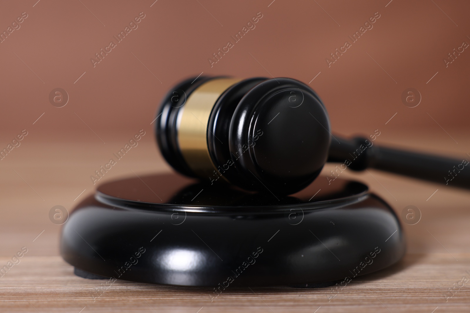 Judge's gavel and sound block on wooden table against brown background, closeup Photo of Judge's gavel and sound block on wooden table against brown background, closeup