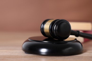 Photo of Judge's gavel and sound block on wooden table against brown background, closeup