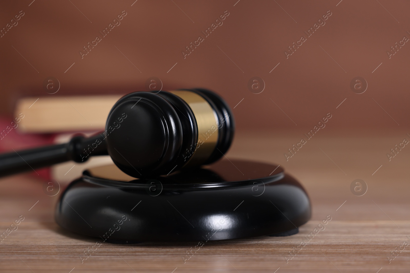 Judge's gavel and sound block on wooden table against brown background, closeup Photo of Judge's gavel and sound block on wooden table against brown background, closeup