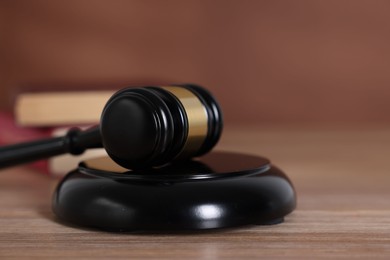 Photo of Judge's gavel and sound block on wooden table against brown background, closeup