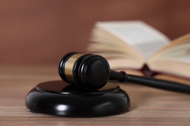 Photo of Judge's gavel and sound block on wooden table against brown background, closeup