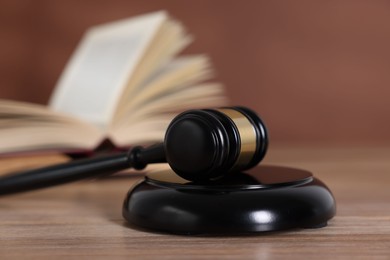 Photo of Judge's gavel and sound block on wooden table against brown background, closeup