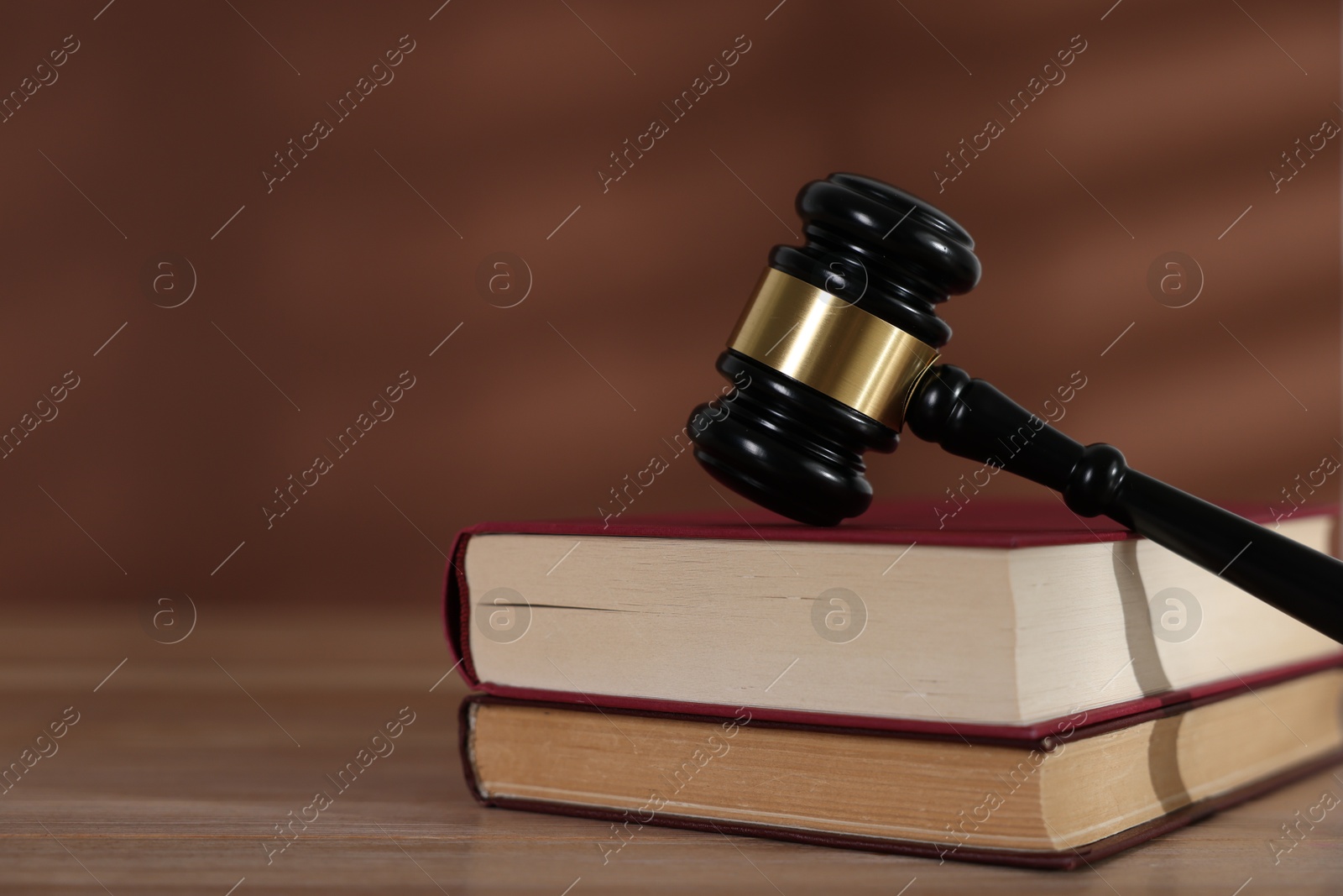 Judge's gavel and books on wooden table against brown background, closeup. Space for text Photo of Judge's gavel and books on wooden table against brown background, closeup. Space for text