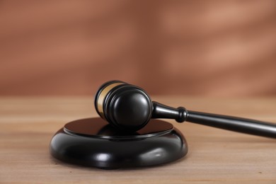Photo of Judge's gavel and sound block on wooden table against brown background, closeup
