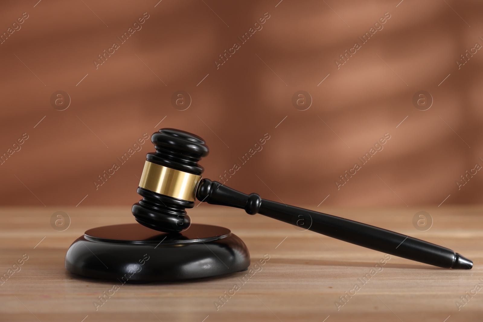 Judge's gavel and sound block on wooden table against brown background, closeup Photo of Judge's gavel and sound block on wooden table against brown background, closeup