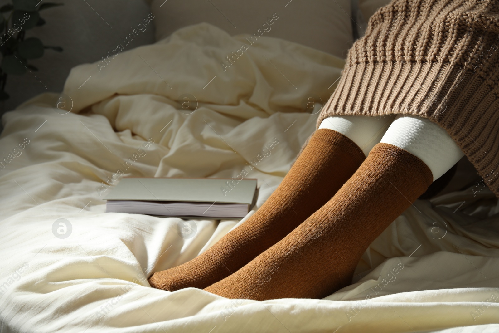 Woman in brown socks on bed at home, closeup Photo of Woman in brown socks on bed at home, closeup