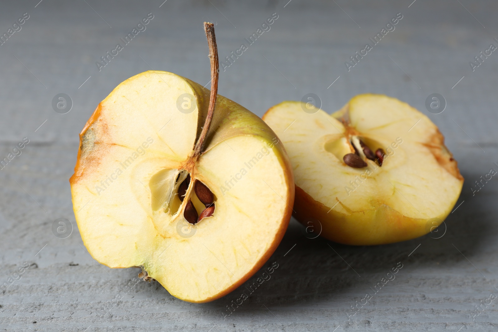 Halves of overripe apple on grey wooden table, closeup Photo of Halves of overripe apple on grey wooden table, closeup