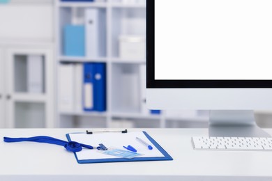 Photo of Doctor's workplace with paperwork, badge and computer on desk. Space for text
