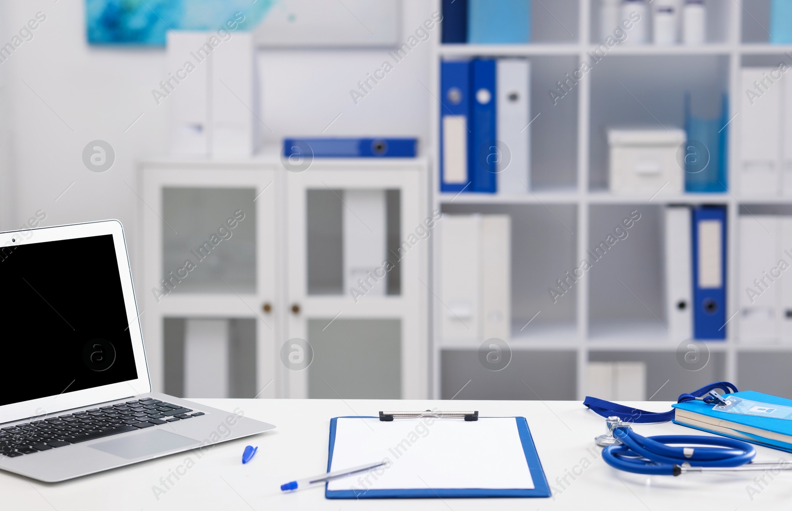 Doctor's workplace with stethoscope, paperwork and laptop on desk. Space for text Photo of Doctor's workplace with stethoscope, paperwork and laptop on desk. Space for text