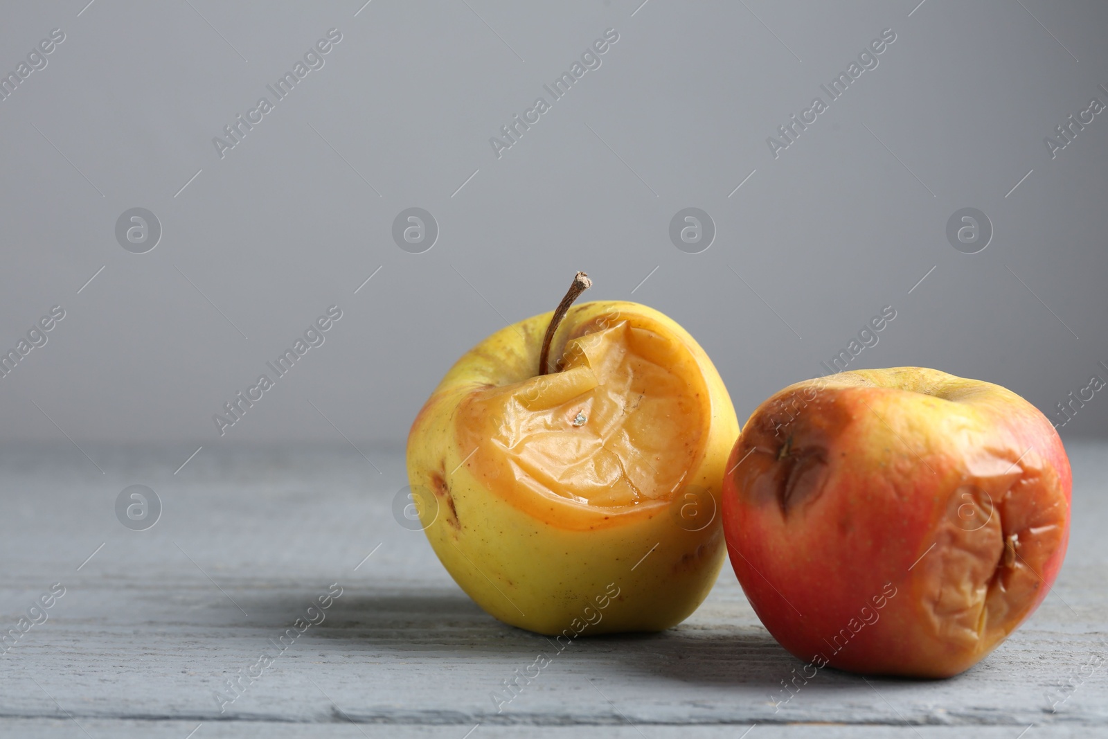 Rotten apples on grey wooden table, closeup. Space for text Photo of Rotten apples on grey wooden table, closeup. Space for text