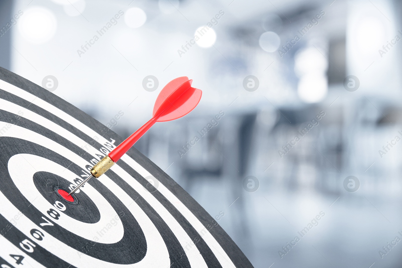 Image of Targeting and business success. Dart sticking in center of dartboard in office, closeup