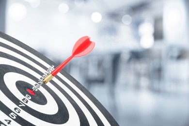 Image of Targeting and business success. Dart sticking in center of dartboard in office, closeup