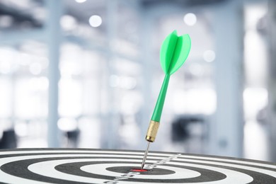 Image of Targeting and business success. Dart sticking in center of dartboard in office, closeup