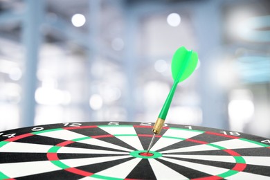 Image of Targeting and business success. Dart sticking in center of dartboard in office, closeup