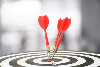 Image of Targeting and business success. Darts sticking in center of dartboard in office, closeup