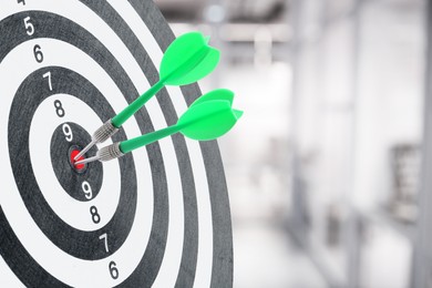 Image of Targeting and business success. Darts sticking in center of dartboard in office, closeup
