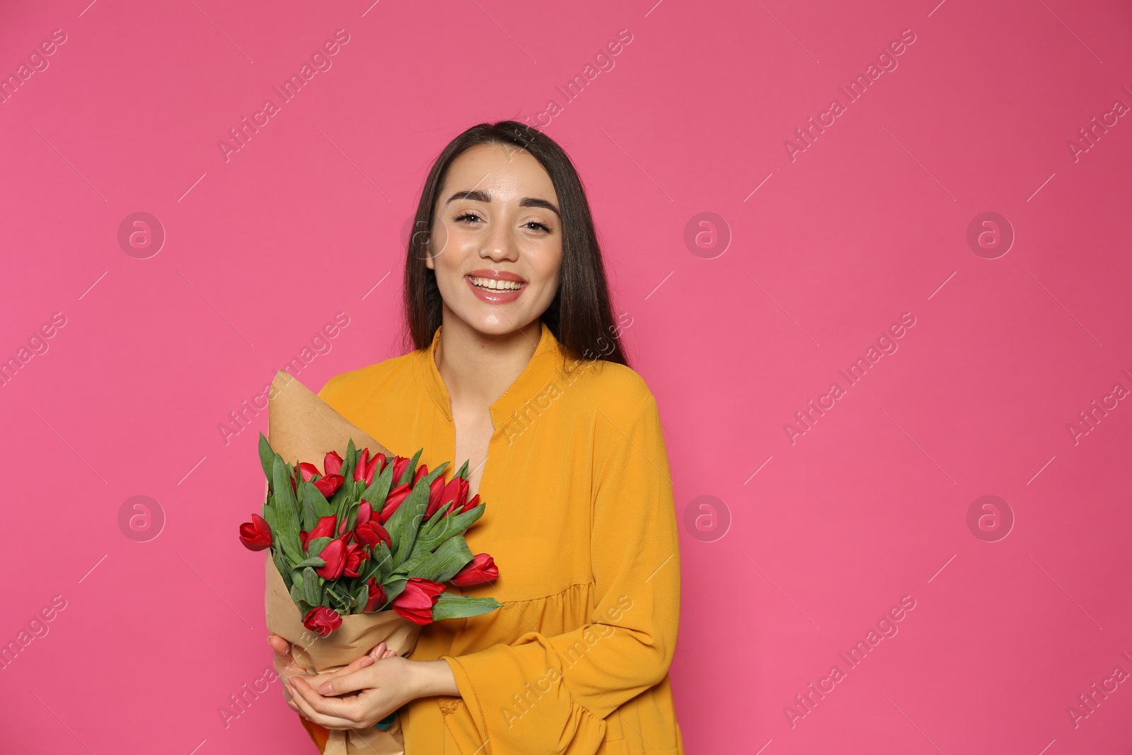 Happy woman with red tulip flowers bouquet on pink background, space for text. 8th of March celebration Photo of Happy woman with red tulip flowers bouquet on pink background, space for text. 8th of March celebration