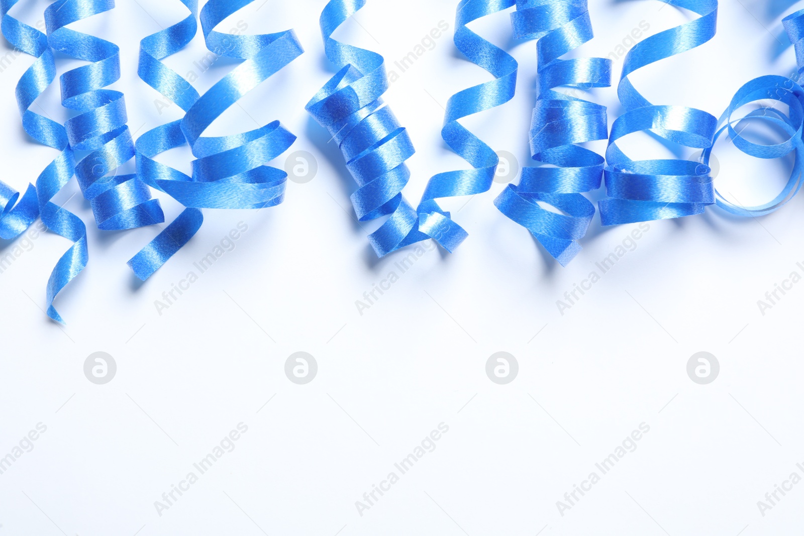 Photo of Blue serpentine streamers on white background, top view