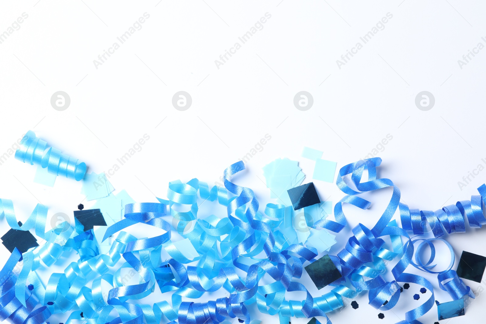 Blue serpentine streamers and confetti on white background, top view Photo of Blue serpentine streamers and confetti on white background, top view
