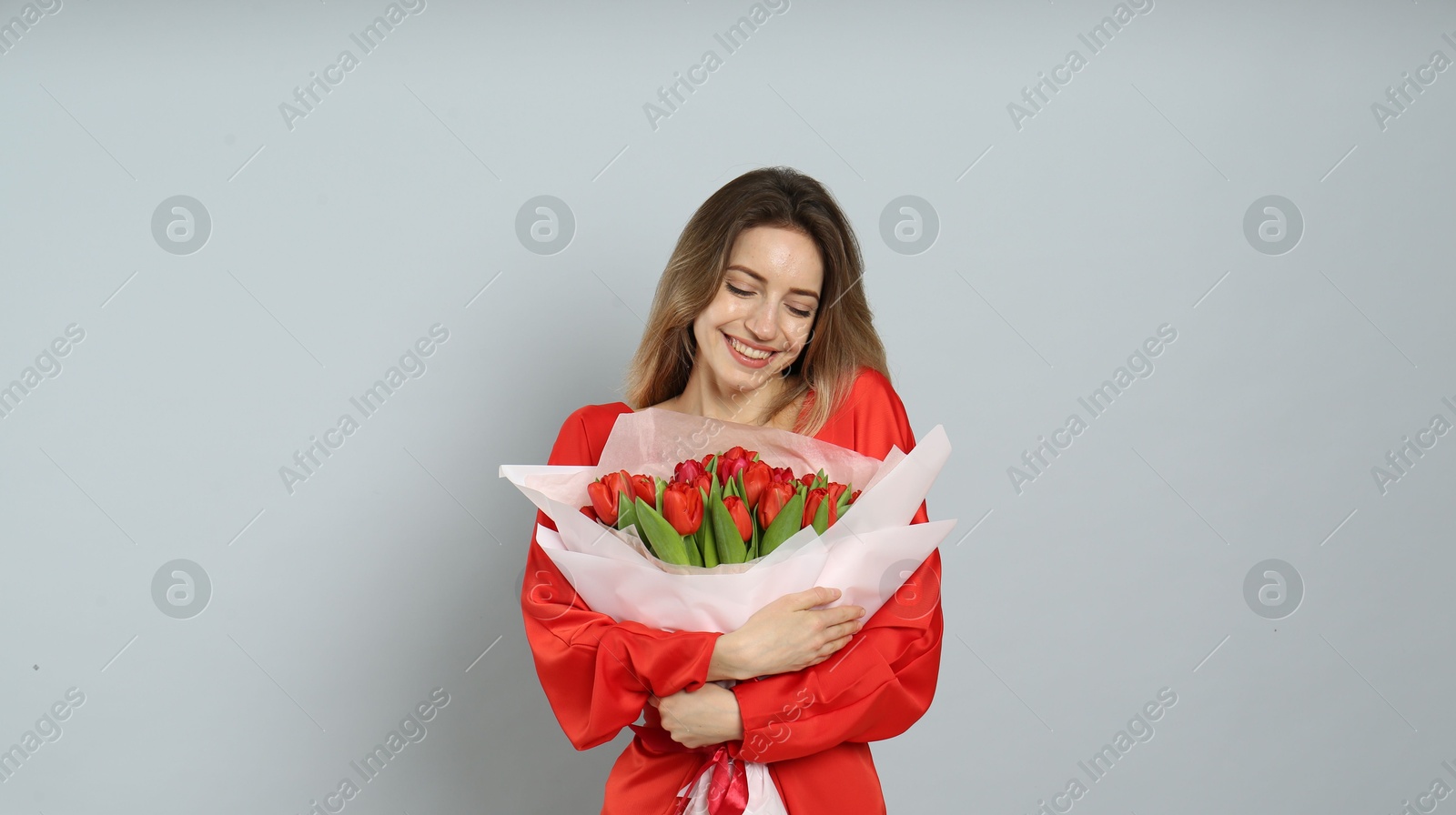 Happy woman with red tulip bouquet on light grey background. 8th of March celebration Photo of Happy woman with red tulip bouquet on light grey background. 8th of March celebration