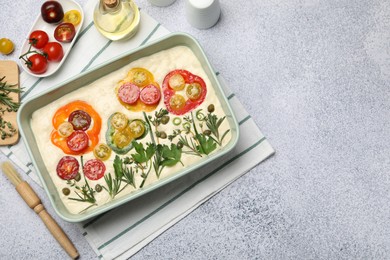 Photo of Raw focaccia with vegetables, spices and brush on grey table, flat lay. Space for text