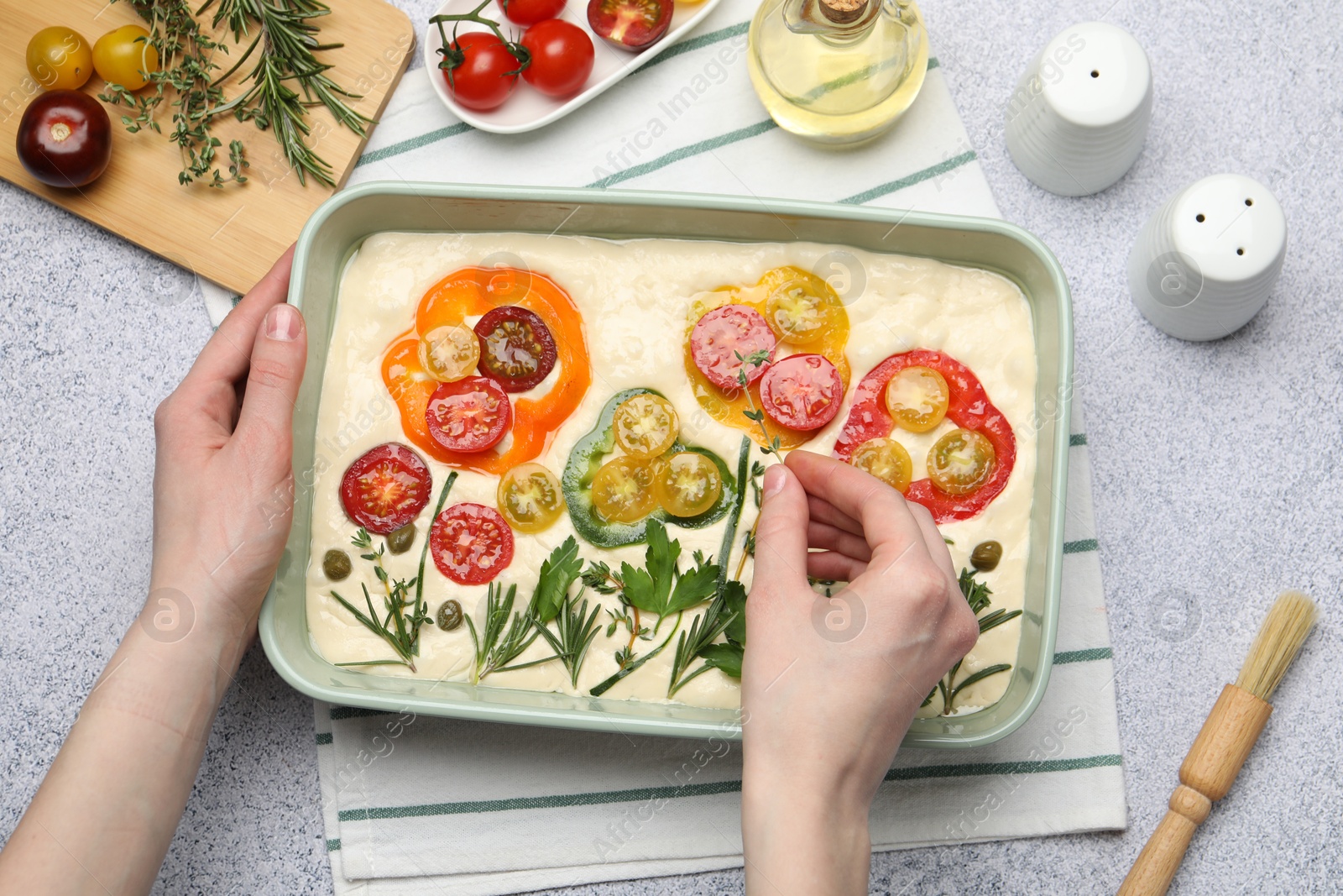Woman adding thyme to raw focaccia at grey table, top view Photo of Woman adding thyme to raw focaccia at grey table, top view