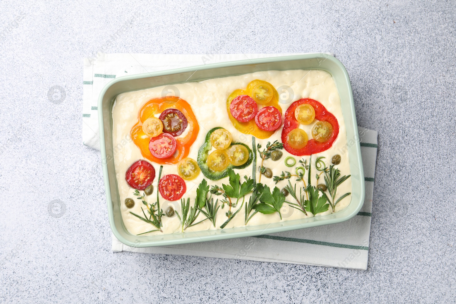 Raw focaccia with vegetables and spices in baking dish on light grey table, top view Photo of Raw focaccia with vegetables and spices in baking dish on light grey table, top view