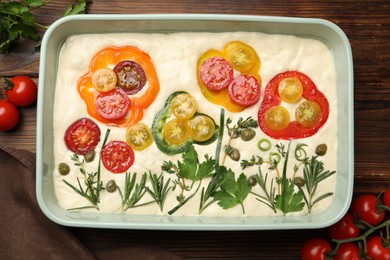 Photo of Raw focaccia with vegetables and spices on wooden table, flat lay