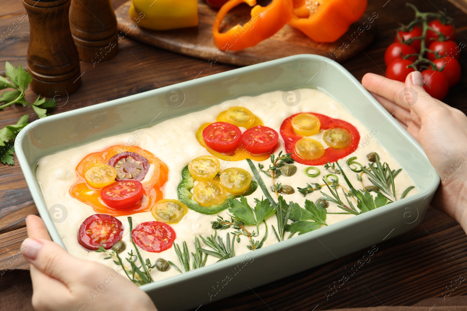 Woman with raw focaccia and ingredients at wooden table, closeup Photo of Woman with raw focaccia and ingredients at wooden table, closeup