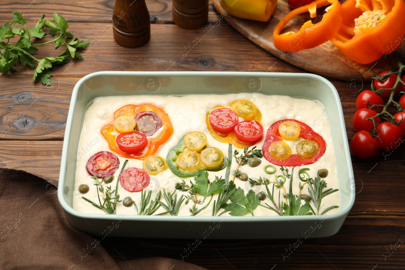 Raw focaccia with vegetables and spices on wooden table Photo of Raw focaccia with vegetables and spices on wooden table