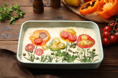Photo of Raw focaccia with vegetables and spices on wooden table
