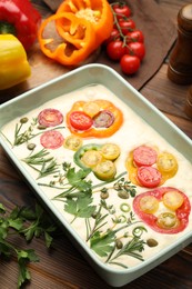 Photo of Raw focaccia with vegetables and spices on wooden table