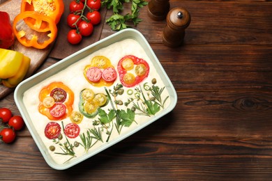 Photo of Raw focaccia with vegetables and spices on wooden table, flat lay. Space for text