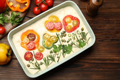 Photo of Raw focaccia with vegetables and spices on wooden table, flat lay
