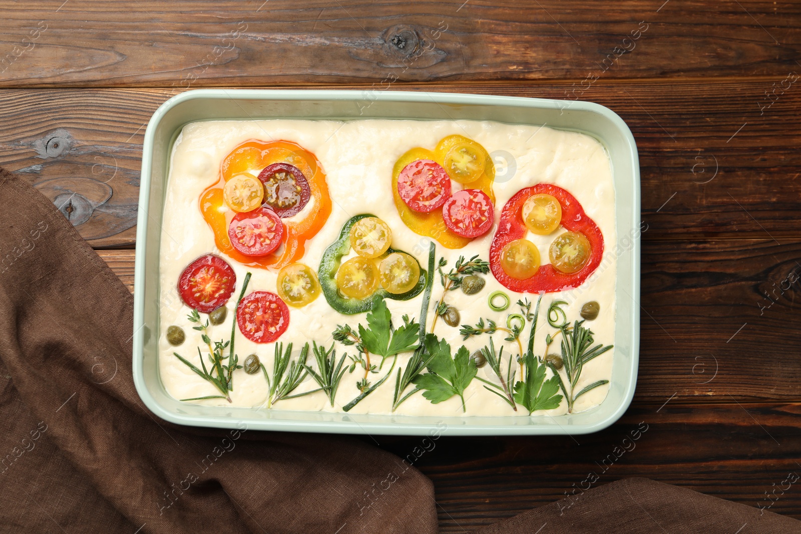 Raw focaccia with vegetables and spices in baking dish on wooden table, top view Photo of Raw focaccia with vegetables and spices in baking dish on wooden table, top view