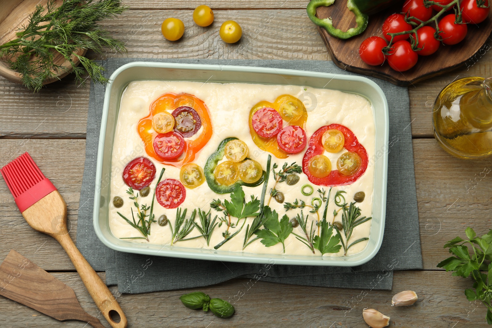 Raw focaccia with vegetables, spices and brush on wooden table, flat lay Photo of Raw focaccia with vegetables, spices and brush on wooden table, flat lay