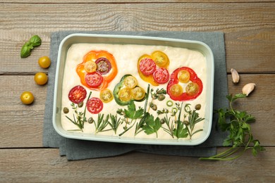 Photo of Raw focaccia with vegetables and spices on wooden table, flat lay