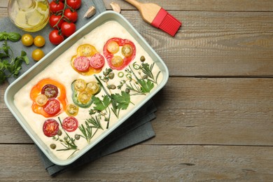 Photo of Raw focaccia with vegetables, spices and brush on wooden table, flat lay. Space for text