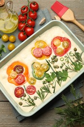 Photo of Raw focaccia with vegetables, spices and brush on wooden table, flat lay