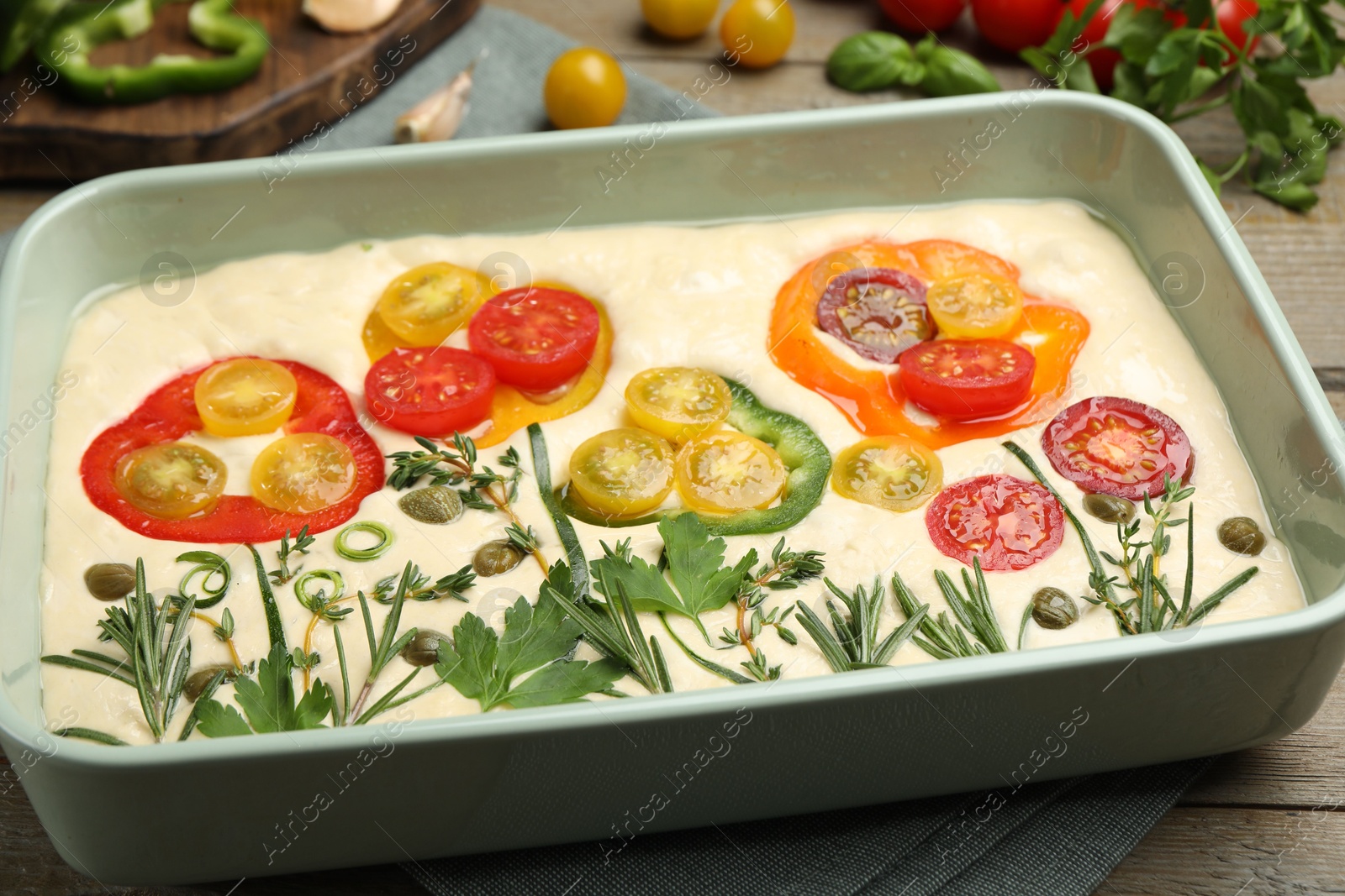 Raw focaccia with vegetables and spices on wooden table, closeup Photo of Raw focaccia with vegetables and spices on wooden table, closeup