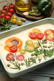 Photo of Raw focaccia with vegetables and spices on table, closeup