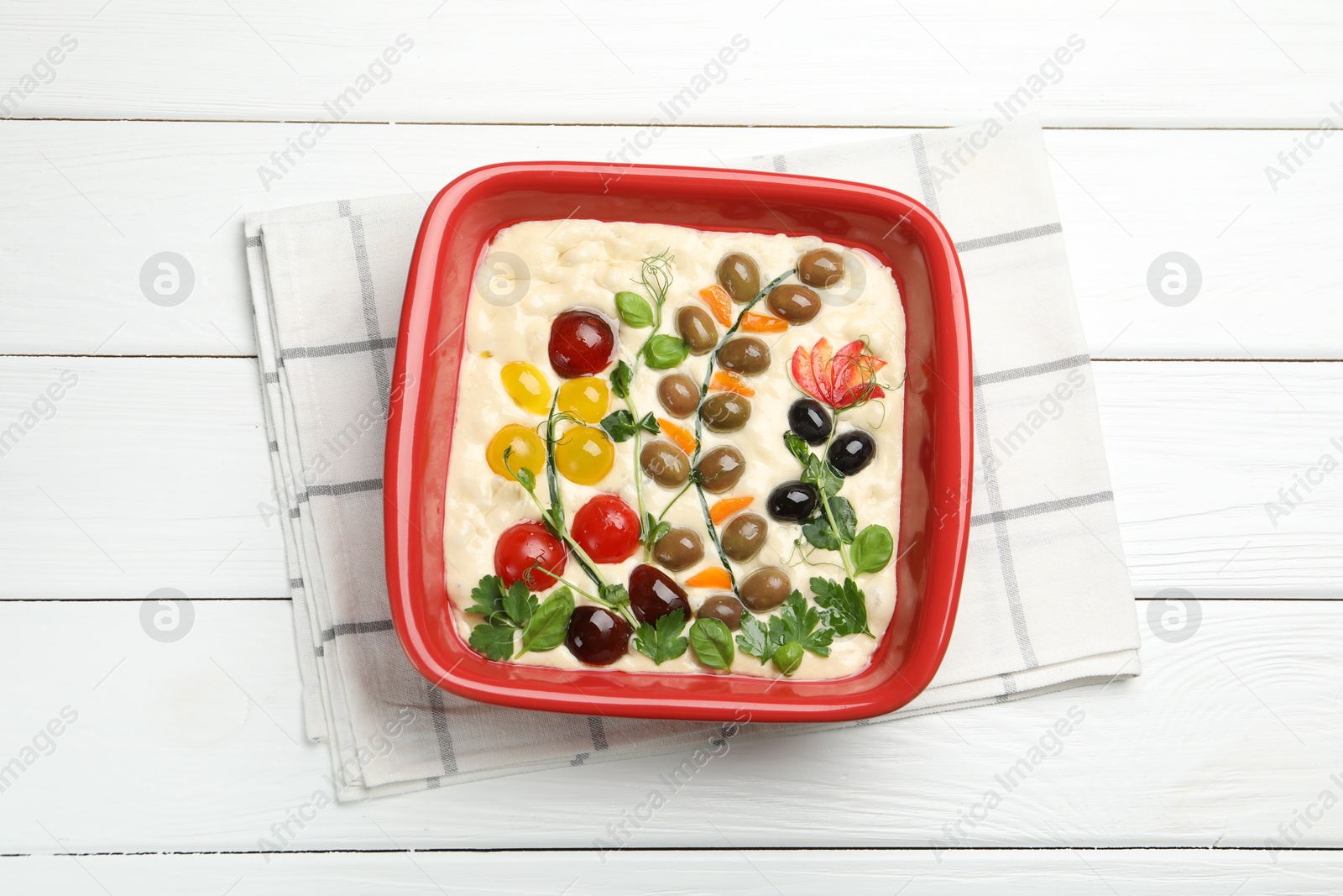 Raw focaccia with vegetables and olives in baking dish on white wooden table, top view Photo of Raw focaccia with vegetables and olives in baking dish on white wooden table, top view