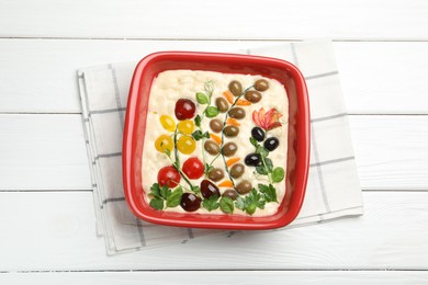 Photo of Raw focaccia with vegetables and olives in baking dish on white wooden table, top view