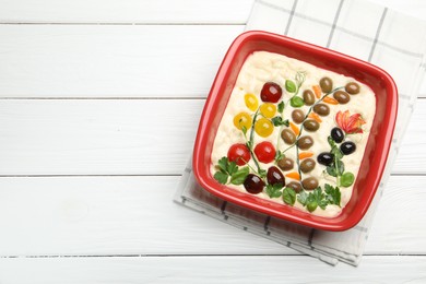 Photo of Raw focaccia with vegetables and olives in baking dish on white wooden table, top view. Space for text