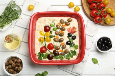 Photo of Raw focaccia with vegetables, olives and spices on white wooden table, flat lay